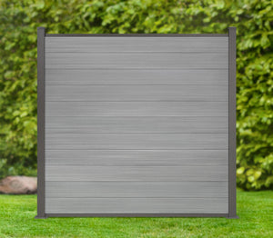 WPC Coex Zaun grau mit anthrazit Posten und Leisten steht vor einer grünen Hecke